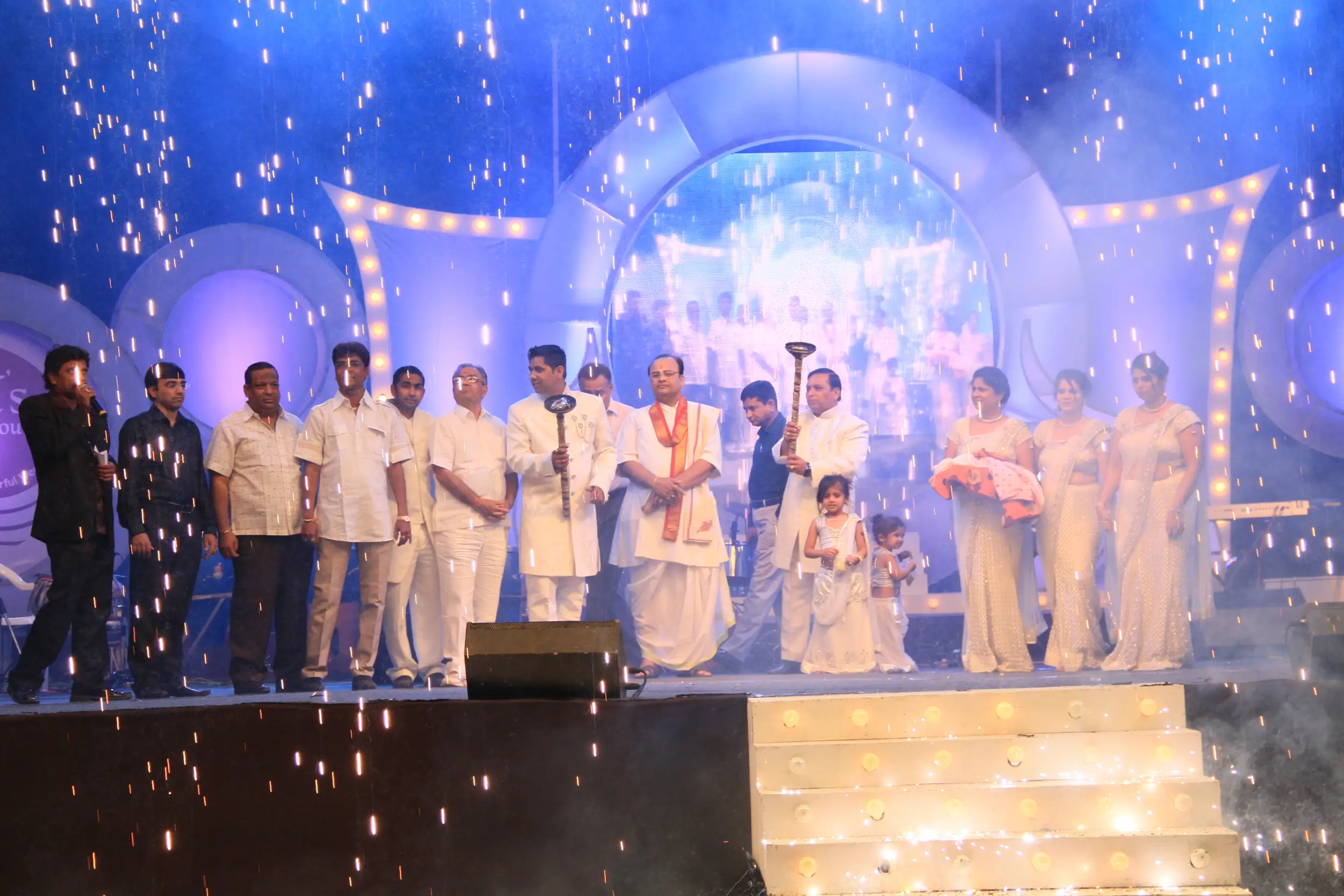 Men lighting ceremonial lamp at event with ITT banner in background